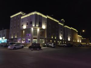 een groot gebouw met auto's geparkeerd op een parkeerplaats 's nachts bij Asfar Plaza Hotel & Apartments in Riyad