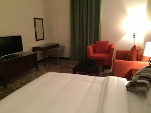 a hotel room with a bed and chairs and a television at Asfar Plaza Hotel & Apartments in Riyadh