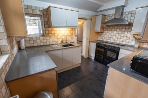a large kitchen with white cabinets and black appliances at Isfryn Holiday Let in Caernarfon