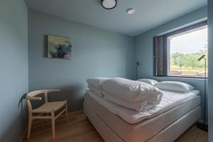 a bedroom with a bed with a window and a chair at Modern Apartment close to Leknes in Leknes