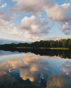 a large lake with a cloudy sky and trees at Uroczy Domek in Złocieniec