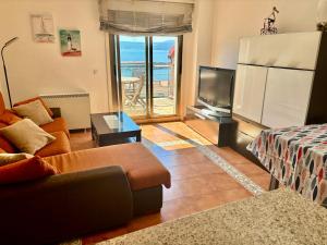 a living room with a couch and a tv at Portosin Sea&Pool in Portosin