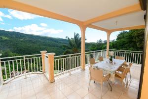 a patio with a table and chairs on a balcony at vue sur la montagne in Pointe-Noire
