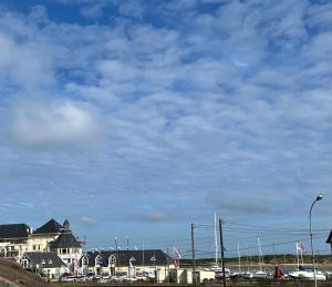 Un cielo azul nublado con casas y barcos en un puerto en maison de la marine, en Dives-sur-Mer