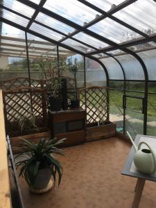 a greenhouse with potted plants and a table in it at La maison d'en face in Valliquerville