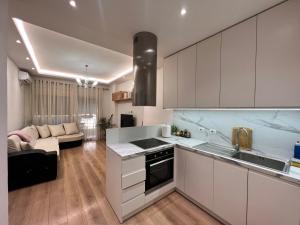 a kitchen with white cabinets and a living room at Tirana modern one bedroom Apartment in Kashari
