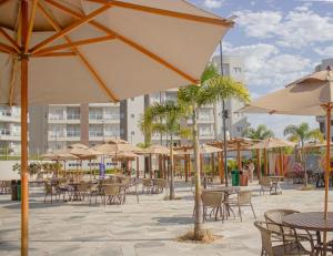 un patio extérieur avec tables, chaises et parasols dans l'établissement Lagoa Eco Towers - Apartamento para ate 7 pessoas com acesso a piscinas, quiosques, restaurante e muito mais, à Caldas Novas
