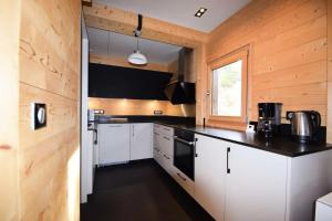 エム・ラ・プラーニュにあるChalet Boulevard - Chalet Boulevard -8 pers - PLAGNE CENTRE, sur les pistes - wifi - CTBOU MAE-6814の白いキャビネットと黒いカウンタートップを備えたキッチン