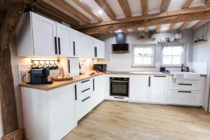 a kitchen with white cabinets and a wooden floor at Gîte Saint Amour in Le Pin