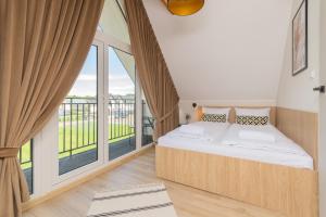 a bedroom with a bed and a large window at Morska Oaza Jantar in Jantar