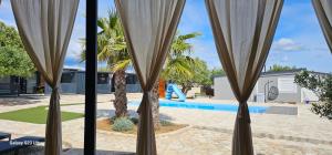a view through the curtains of a house with a swimming pool at SAK Mobile Home Pirovac in Pirovac