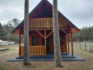 a log cabin with trees in front of it at Domki letniskowe OSTROWITE in Ostrowite