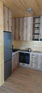 a kitchen with wooden cabinets and a stainless steel refrigerator at Domki letniskowe OSTROWITE in Ostrowite