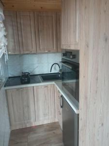 a kitchen with wooden cabinets and a sink and a stove at Domki letniskowe OSTROWITE in Ostrowite +6 photos