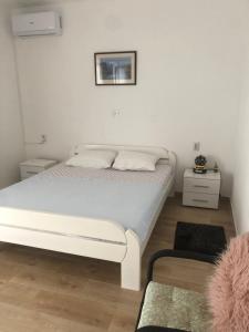 a bedroom with a white bed and a picture on the wall at Very spacious - fully air conditioned - apartment nearby Vir bus station in Vir