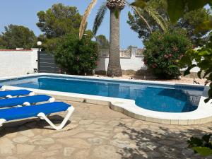 a blue swimming pool with two chairs and a palm tree at COLOMBIA piscina privada in Miami Platja