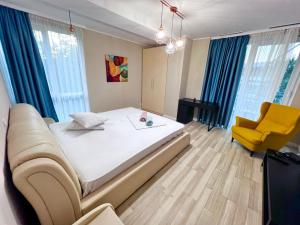 a bedroom with a large bed and a yellow chair at Coralia Luna Park Apartments in Mamaia