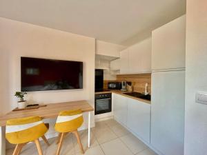 a kitchen with a wooden table and two yellow chairs at Studio à l'Ecurie in Narbonne