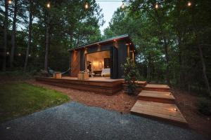 a small cabin in the woods with a bed in it at Glamping cottage with glass front and hot tub! in Guntersville +4 photos
