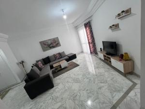 a living room with a couch and a television at Appartement slim centre sousse in Sousse