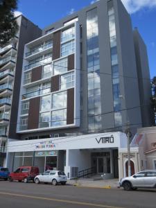 Un edificio alto con coches aparcados delante. en Wales Ave. Apartment, en Puerto Madryn