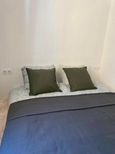 a bed with two green pillows on top of it at Santa Banana Apartment Alicante in Alicante