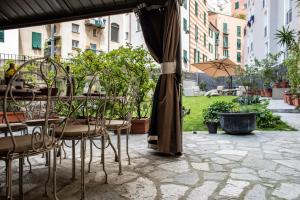 un patio con tavoli, sedie e un ombrellone di GIARDINO IN CENTRO STORICO - Appartamento con giardino, Genova Centro Storico, Acquario a Genova Altre 20 foto