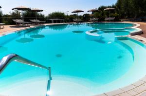 a large blue swimming pool with chairs and umbrellas at Park Hotel Cilento in Marina di Camerota