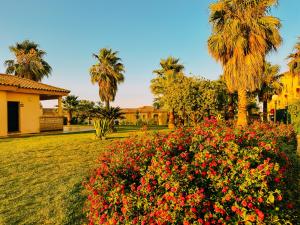a garden with flowers and palm trees and a building at Mika's House Valley in Sanlúcar de Barrameda