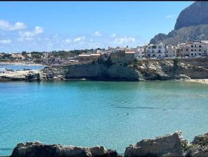 una playa con agua azul y edificios de fondo en Sicilia biedda casa vacanze, en Terrasini