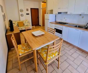 una cucina con tavolo e sedie in legno e una cucina con elettrodomestici bianchi di Residence azzurro VISTA MARE-A a Gabicce Mare 1 altra foto
