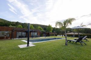a yard with a pool and two chairs and an umbrella at Refúgio das Oliveiras, Mondim de Bastos in Mondim de Basto