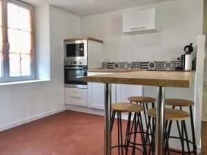 a kitchen with a counter and stools in it at Gite de nounours à beauval in Seigy