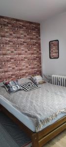 a bed in a room with a brick wall at Apartament Lubin in Lubin