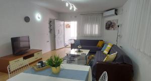 a living room with a blue couch and a tv at Knezevic House in Gevgelija