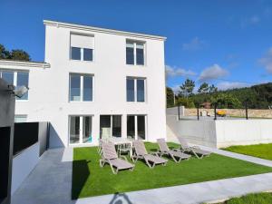 a white house with chairs on a lawn at Casa Manolo de Amparo in Vimianzo