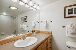 Un baño con lavabo, inodoro y espejo. en Lodge at Lionshead 408, en Vail