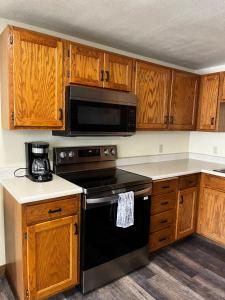 a kitchen with wooden cabinets and a black stove top oven at ParkWay Yellowstone Riverside Studio #6 in Gardiner