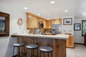 Una cocina con gabinetes de madera y un mostrador con taburetes. en Lodge at Lionshead 408, en Vail