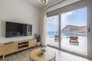 a living room with a tv and a sliding glass door at Villa Pava-sea view brand new villa in Archangelos