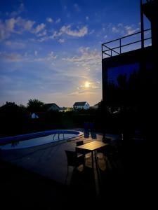a sunset over a pool with a table and chairs at Ailleurs in Novi Banovci