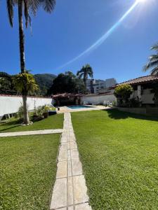 a pathway through a grassy yard with palm trees at Praia das Toninhas - Condomínio Summer Time APTO 33 in Ubatuba