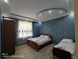 a bedroom with two beds and a blue wall at Hillside villa in Gabala