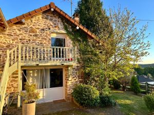 a stone house with a white door and a balcony at Au Pied du Frêne in Bourganeuf