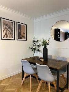 Una mesa de comedor con sillas blancas y un espejo. en Excellent Apartment for Familly, en Clichy
