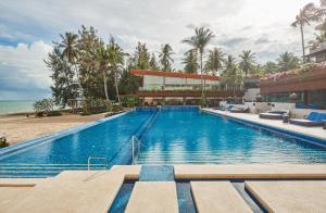 a swimming pool next to a beach with a building at Dhevan Dara Beach Villa Kuiburi in Kui Buri