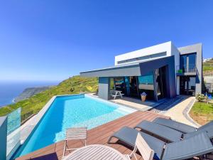 a house with a swimming pool next to the ocean at Villa Leonor Cliffside Retreat in Calheta