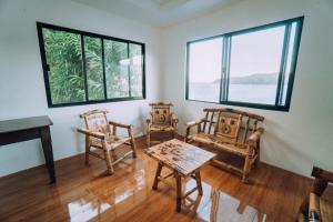 ein Raum mit Stühlen und einem Tisch und Fenstern in der Unterkunft Soul Shine Beach House in Bacungan