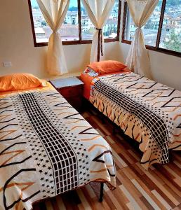 2 camas en una habitación con ventanas en La Casa Quiteña, en Quito
