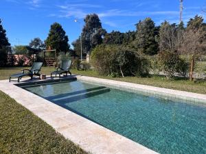 a swimming pool with two chairs in a yard at Parada Nomade in Los Cardales